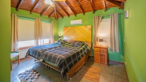 A bedroom with a wooden ceiling, a bed with a plaid bedspread, a nightstand, and a window with curtains. - Tranquilo! (Cafayate)