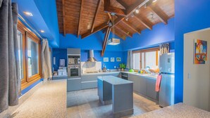 A modern kitchen with blue walls, wooden ceiling beams, and stainless steel appliances. - Tranquilo! (Cafayate)
