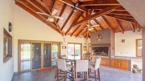 A spacious kitchen with a large island, wooden ceiling beams, and a dining area with chairs. - Tranquilo! (Cafayate)