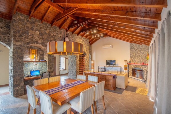 Un vaste espace dédié à la salle à manger, avec une table et des chaises en bois, un mur en pierre et une cheminée.