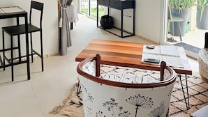 A modern living space with a wooden dining table, a sofa, a TV, and a view of the outdoors. - Cosy (Apt7) - Patio, Sea View and pool (indigo Bay)