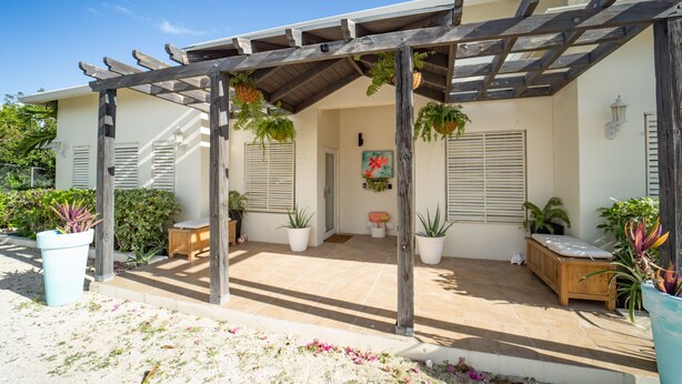 En overdækket terrasse med træpergola, plantekasser og en bænk.