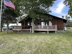 A wooden cabin with a porch and a flagpole.