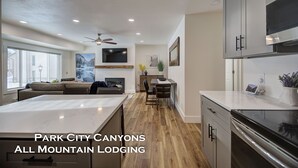 A modern kitchen with a large island, wooden flooring, and built-in appliances. - Canyons View 06: 2 Bed 2 bath walk to the lift (Park City)