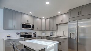 A modern kitchen with grey cabinets, stainless steel appliances, and a central island. - Canyons View 06: 2 Bed 2 bath walk to the lift (Park City)