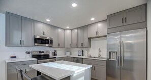 A modern kitchen with stainless steel appliances, grey cabinets, and a central island.
