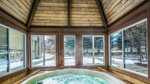 A hot tub in a room with large windows and wooden walls. - Canyons View 06: 2 Bed 2 bath walk to the lift (Park City)