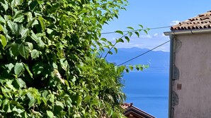Ein Steinhaus mit Blick auf das Meer und Berge im Hintergrund.
