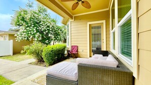 Une terrasse couverte avec un canapé en osier et un ventilateur de plafond.