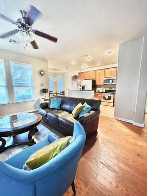 A living room with a sofa, a coffee table, and a ceiling fan.