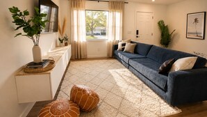 Un salon avec un canapé, une table basse, un tapis et une plante en pot.