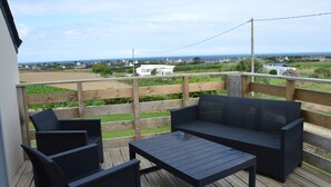 A wooden deck with outdoor furniture, a view of houses and the sea. - Furnished, 2 stars, with sea view (Plouescat)