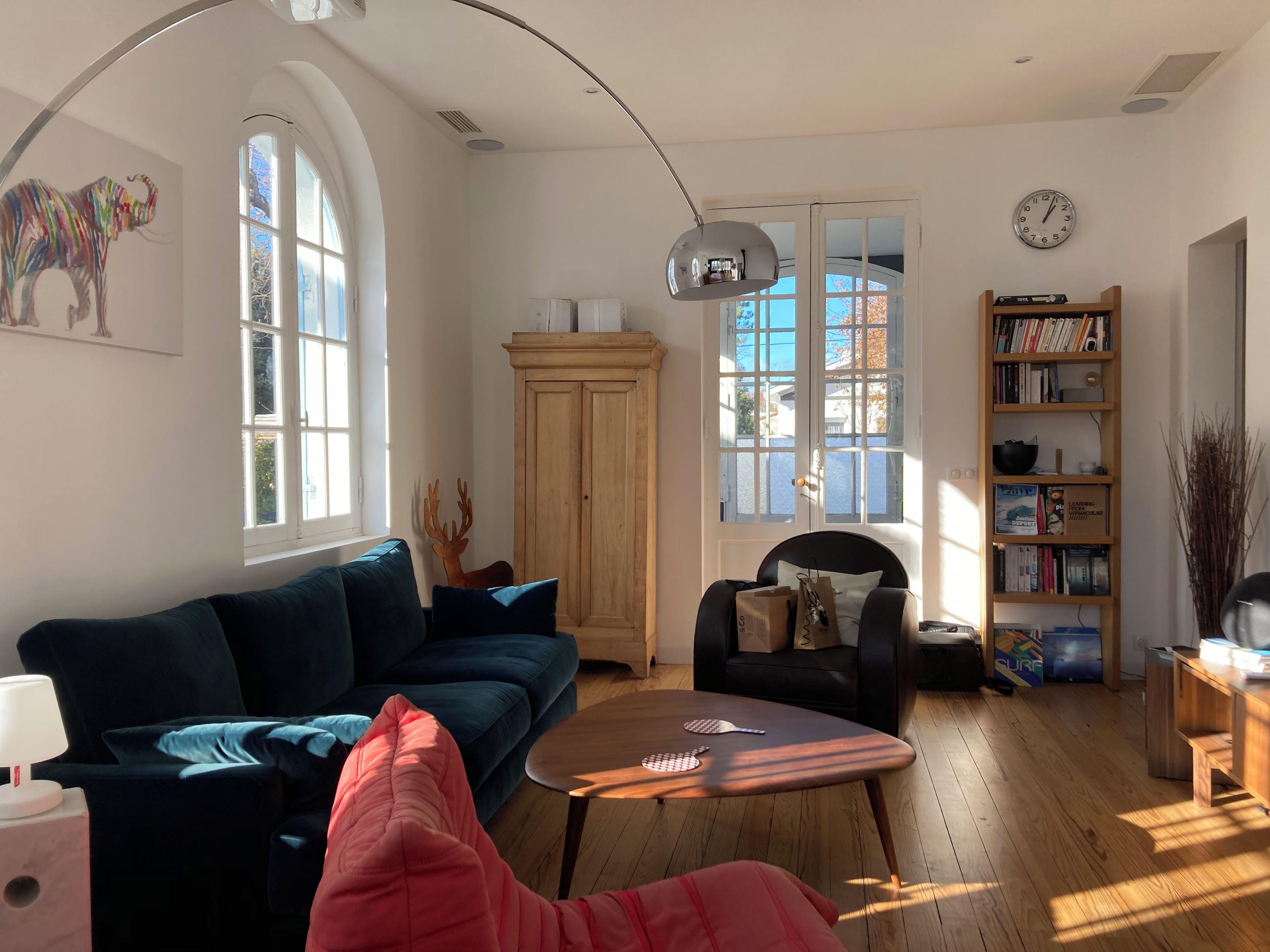 Uma sala de estar com sofá, poltrona, mesa de centro e estante de livros.