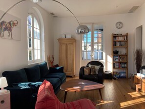 Ein Wohnzimmer mit Sofa, Sesseln, Couchtisch und Bücherregal.