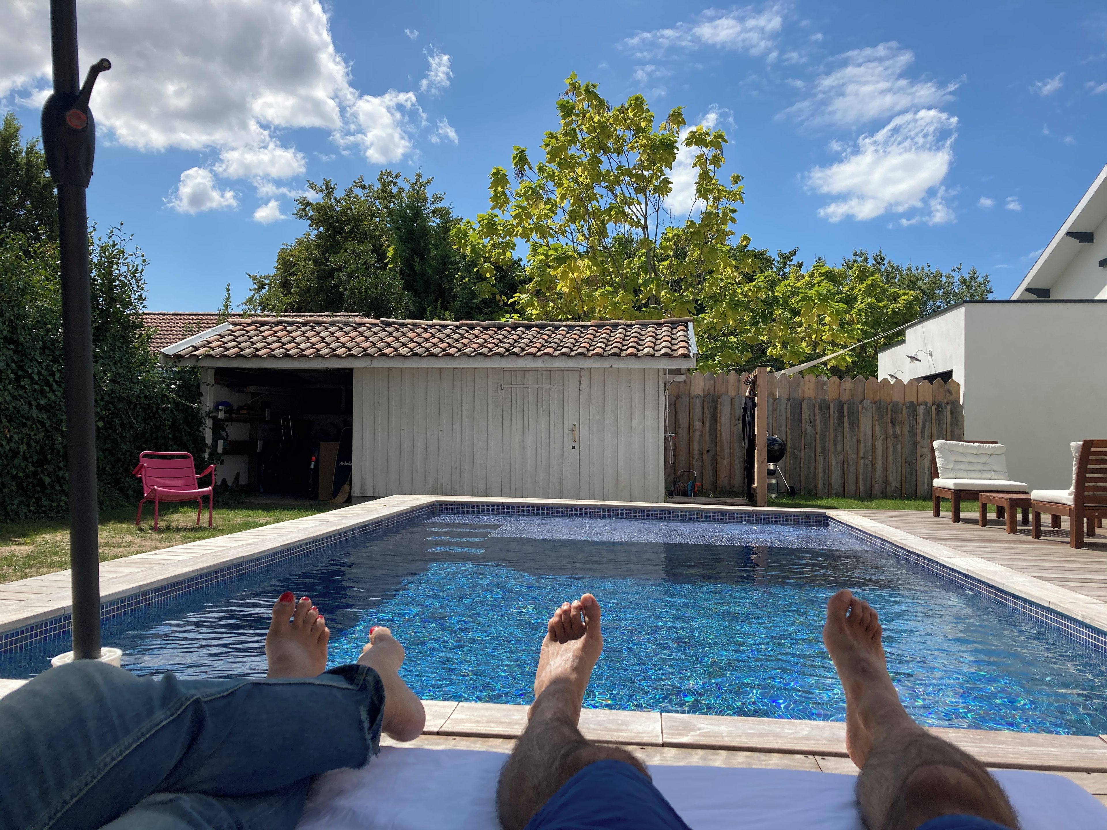 A swimming pool with a tiled edge, a wooden deck, and a red bench.