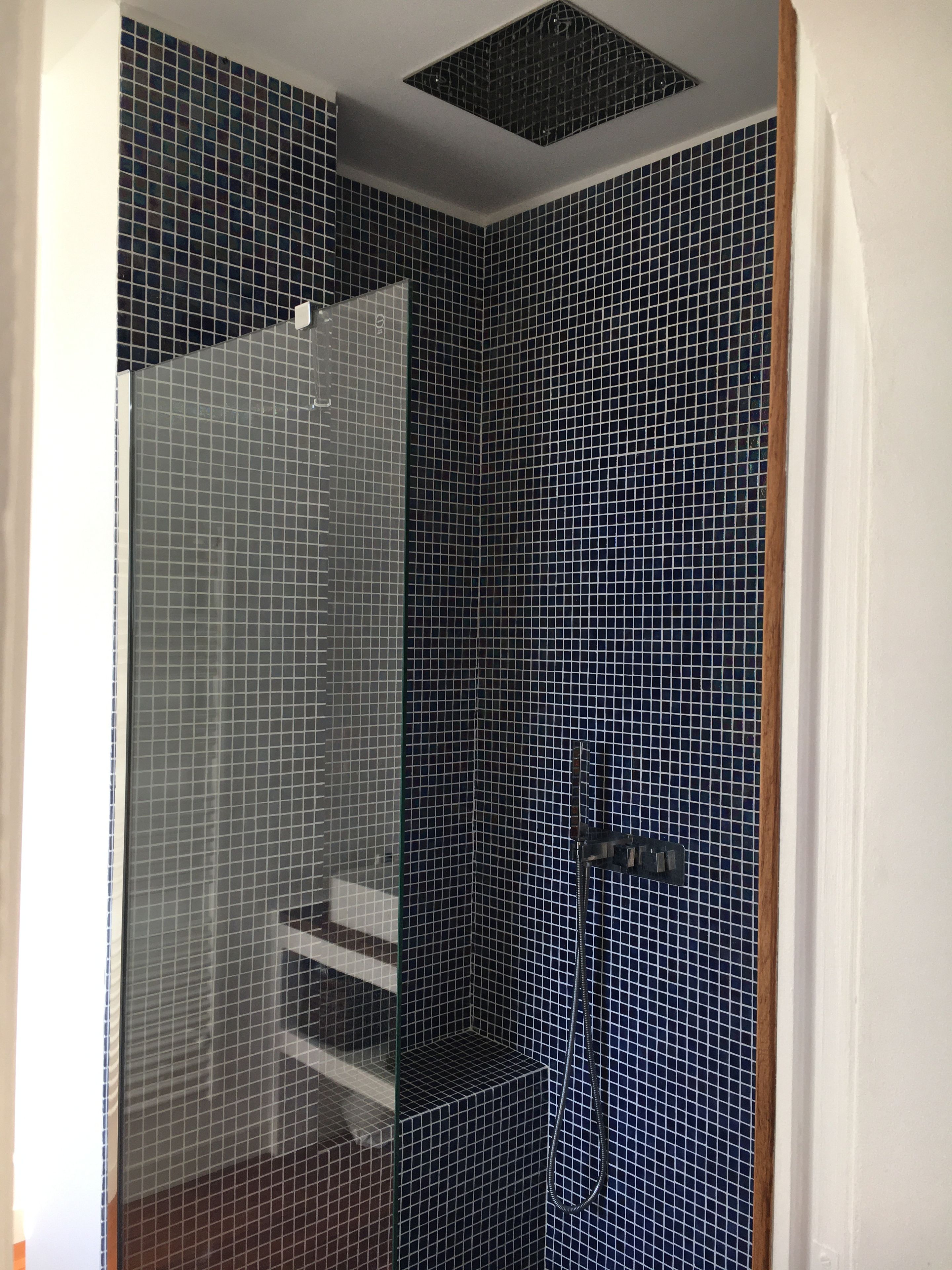 A bathroom with a tiled shower enclosure and a visible showerhead.