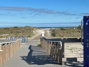 Ein hölzerner Steg führt zu einem Strand mit freiem Blick auf den Ozean.