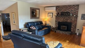 Una sala de estar con chimenea, un sofá de cuero negro, una mesa de centro y una lámpara.