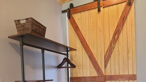 A room with a wooden floor, a metal shelf with baskets, and a wooden barn-style door. - Riverside "Barndominium" w/ easy access to water (Eureka Springs)
