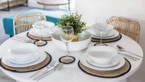 A round dining table set with white plates, silverware, and glassware, centered with a decorative bowl and a small plant. - Seas the Day - Moments from Hamworthy Beach (Poole)