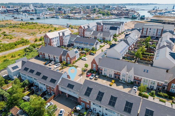 Vista aérea de una zona residencial con casas modernas, un puerto deportivo y un puente al fondo.