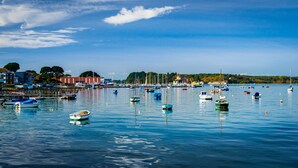 A marina with various boats docked, calm water, and buildings in the background. - Ocean Breeze - Two Bedroom Apartment with Parking (Poole)