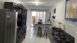 A kitchen with a refrigerator, stove, stools, and a window. - Feet in the Sand. (Arraial do Cabo)