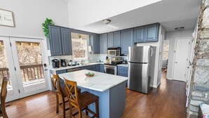 A modern kitchen with blue cabinets, a large island, and stainless steel appliances. -  Long Range Mtn View Hottub Game Room Firepit Grill Fireplace close to Asheville (Fairview)