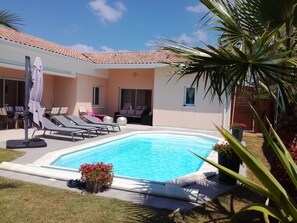 A swimming pool with lounge chairs and a covered seating area.