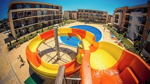 Un parc aquatique doté de nombreux toboggans et d’une piscine, entouré d’immeubles à plusieurs étages avec des balcons.