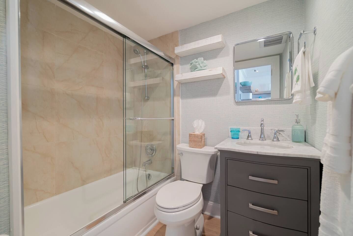 Ein Badezimmer mit Duschkabine, Toilette, Waschbecken mit Spiegel und Handtuchhalter.