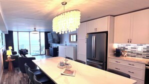 Cozinha moderna com uma ilha grande, eletrodomésticos de aço inoxidável e um lustre.