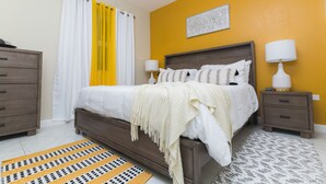 A bedroom with a bed, bedside tables, a dresser, and a patterned rug. - Luxurious 2 bed 2 bath in Kingston city center (Kingston)