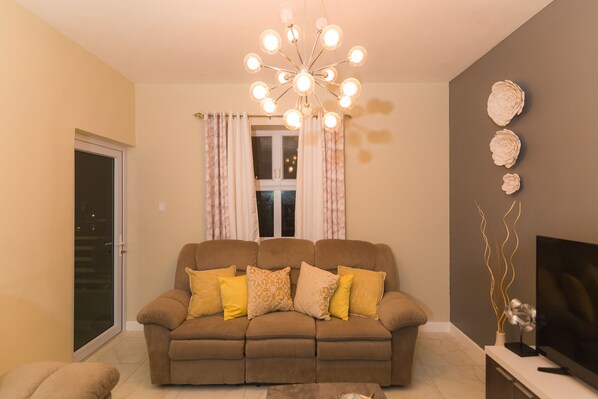 A living room with a sofa, a TV, and a decorative light fixture.