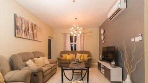 A living room with a sofa set, a coffee table, a TV, and a decorative vase. - Luxurious 2 bed 2 bath in Kingston city center (Kingston)