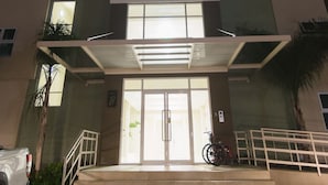 A multi-story building with a central entrance, a covered area, and a staircase leading up to the entrance. - Luxurious 2 bed 2 bath in Kingston city center (Kingston)