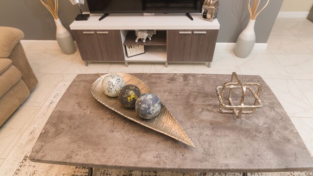 A living room with a modern TV stand, a coffee table with decorative spheres, and a vase with dried reeds. - Luxurious 2 bed 2 bath in Kingston city center (Kingston)