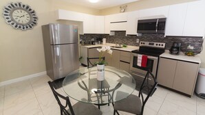 A modern kitchen with a glass dining table, stainless steel appliances, and white cabinetry. - Luxurious 2 bed 2 bath in Kingston city center (Kingston)