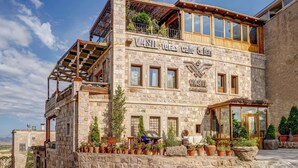 A stone building with a balcony and potted plants.