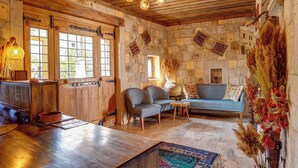 A rustic interior with stone walls, wooden furniture, and a traditional chandelier.