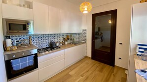 Et moderne køkken med hvide skabe, en mikrobølgeovn, en komfur og et flisebeklædt bagpanel.
