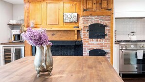 A kitchen with wooden cabinets, a brick fireplace, a coffee maker, and a vase with flowers.