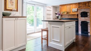 A kitchen with white cabinetry, a brick oven, and a large window.
