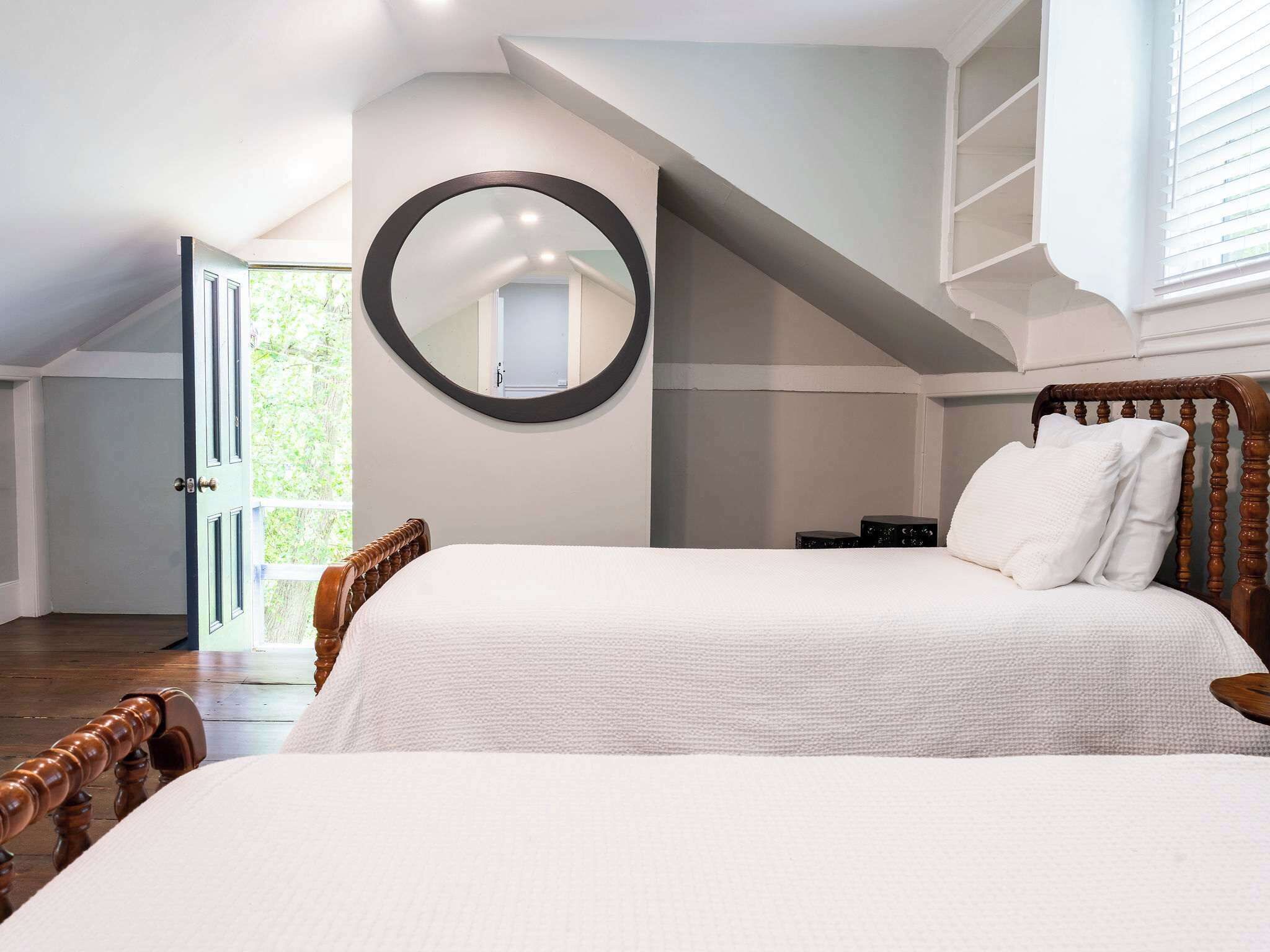 Una camera da letto con un letto grande, uno specchio rotondo e un soffitto spiovente.