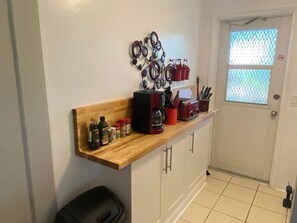 A kitchen with a wooden countertop, a coffee machine, and various kitchen utensils.