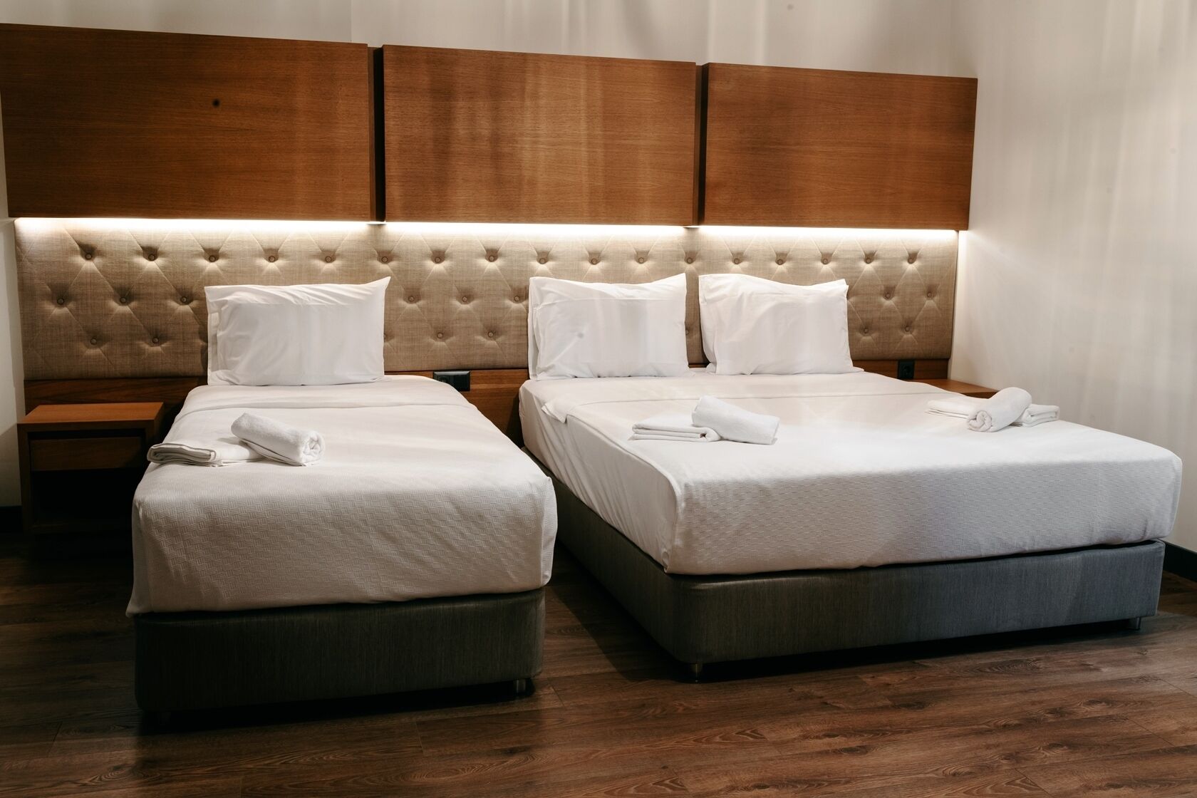 Une chambre d’hôtel avec deux lits, chacun doté d’une tête de lit capitonnée et de linge de lit blanc.