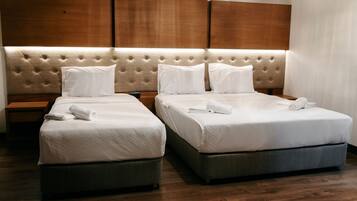 Une chambre d’hôtel avec deux lits, chacun doté d’une tête de lit capitonnée et de linge de lit blanc.