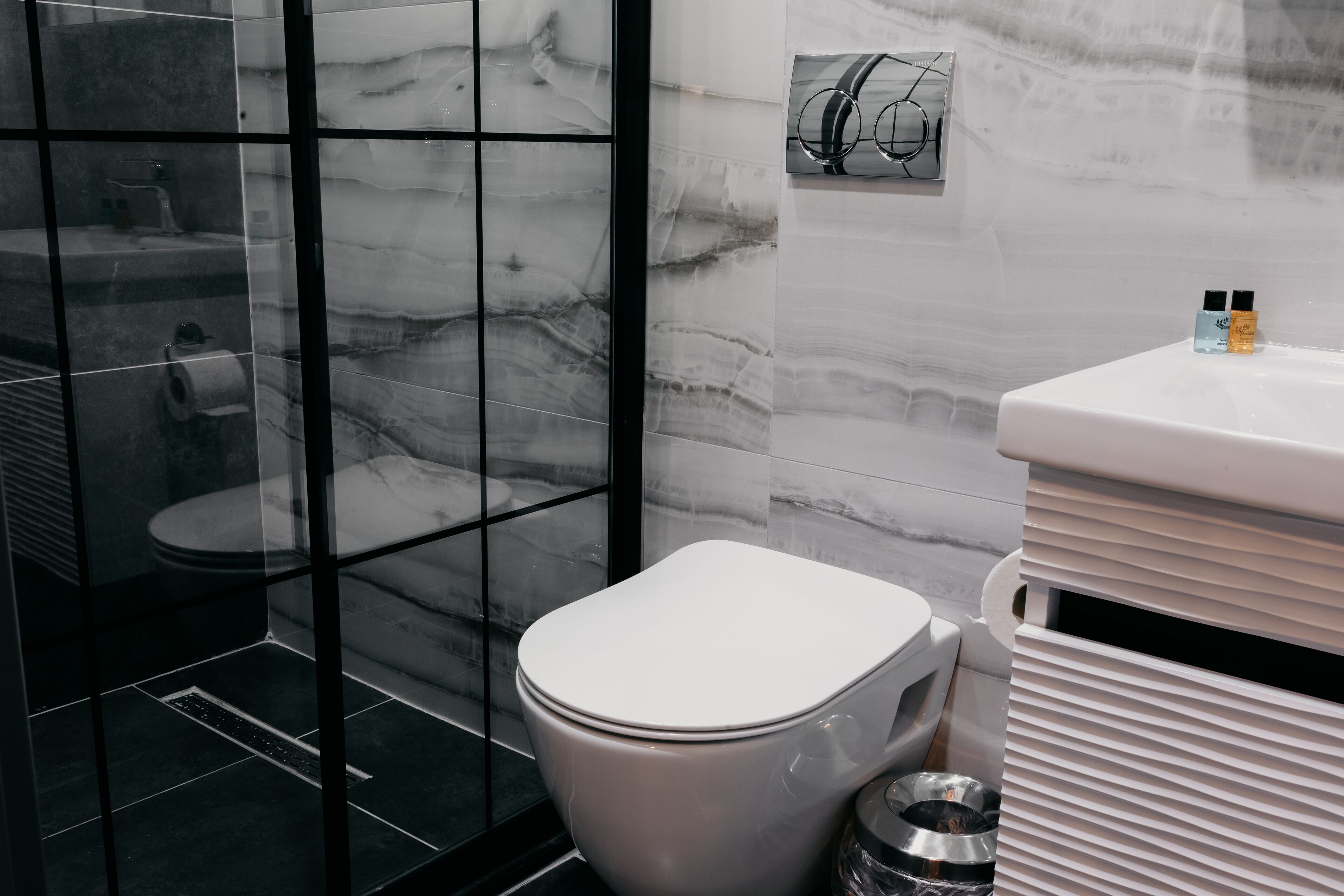 A modern bathroom with a toilet, a bidet, and a trash bin.