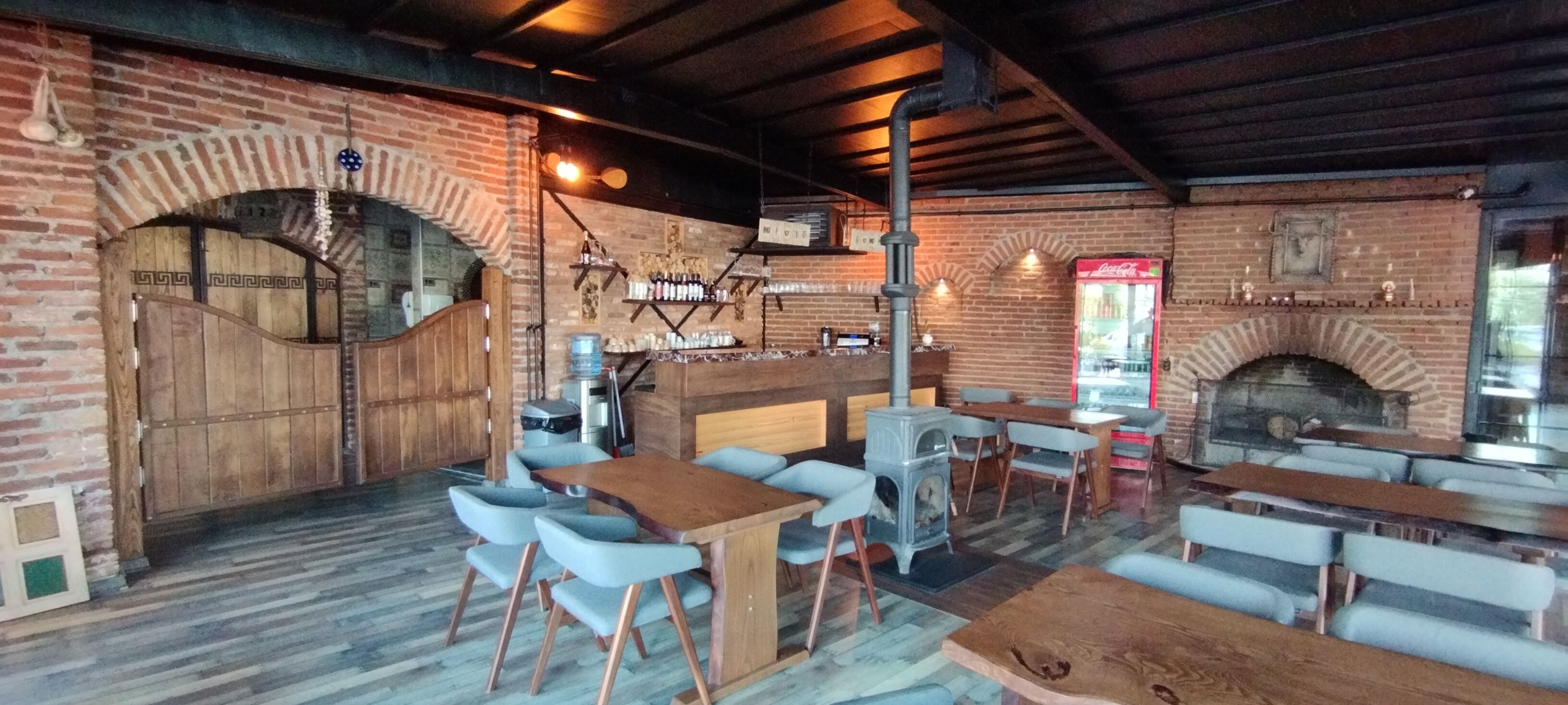 Un ristorante rustico con pareti in mattoni, arredi in legno e un camino in muratura.