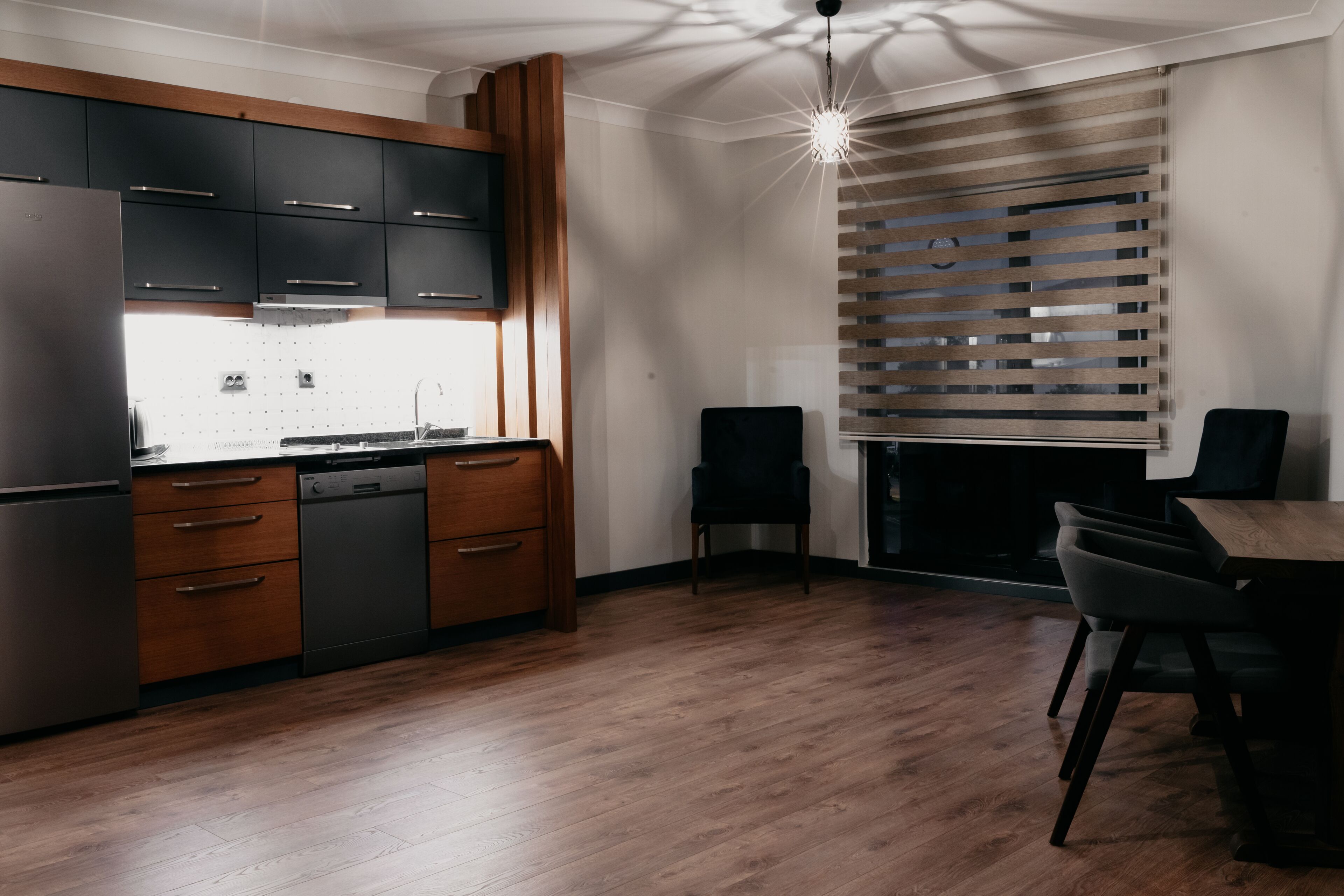 Eine moderne Küche mit Holzschränken, einem Geschirrspüler und einem Essbereich mit Tisch und Stühlen.